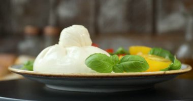 Fesleğen ve domatesli nefis burata peyniri masada dönüyor, yakın plan.