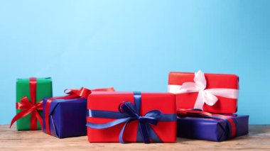 Hediye kutusunu açık mavi arka plana karşı ahşap masaya koyan kadın, yakın plan. Mutlu Noeller ve mutlu yıllar.