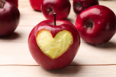 Yüreği oyulmuş olgun bir elma ve açık ahşap bir masa üzerinde, yakın plan.