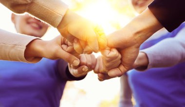 Güneşli bir günde dışarıda yumruk tokuşturan bir grup gönüllü, yakın plan. Pankart tasarımı