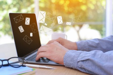 E- posta bildirimi. Masada dizüstü bilgisayar kullanan adam, yakın plan. Ekranda uçuşan harfler