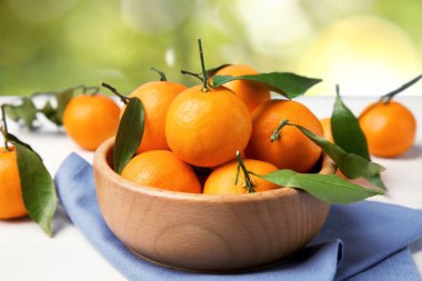 Taze, sulu mandalinalar ve beyaz masada bulanık yeşil arka planda bir sandık.