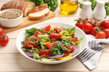 Lezzetli mercimek salatası ve malzemeler açık ahşap masada, yakın plan.