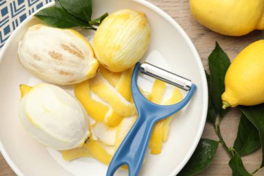 Lezzetli taze limonlar, soyucu ve yapraklar ahşap masa, düz uzanmış