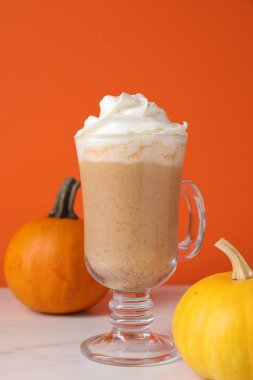 Krem şantili ve taze sebzeli balkabaklı latte turuncu arka planda, yakın planda.