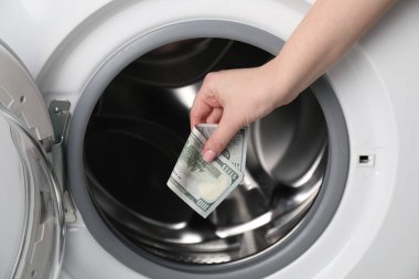 Çamaşır makinesine dolar koyan kadın, yakın plan.
