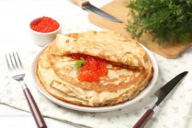 Kırmızı havyarlı leziz krepler ve beyaz ahşap masadaki dereotlar, yakın plan.