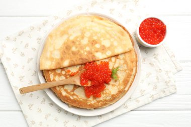 Beyaz ahşap masada kırmızı havyarlı leziz krepler.