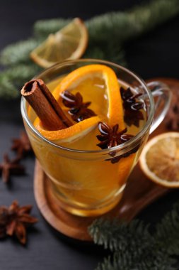 Lezzetli, portakallı, baharatlı ve köknar dallı beyaz şarap siyah ahşap masada, yakın plan.