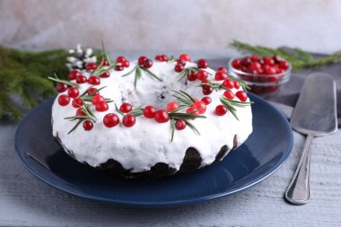 Gri ahşap masada yaban mersinli ve biberiyeli lezzetli Noel pastası, yakın plan.
