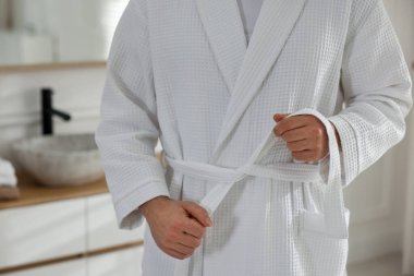 Bornozun kemerini bağlayan adam içeride, yakın plan.