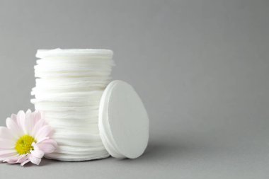 Açık gri arka planda temiz pamuk pedleri ve çiçek yığını, yakın plan. Metin için boşluk