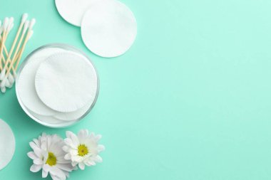 Turkuaz arka planda temiz pamuk pedleri, bezler ve çiçekler, düz yatak. Metin için boşluk