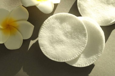 Gri arkaplanda temiz pamuk pedler ve çiçekler, yakın plan.