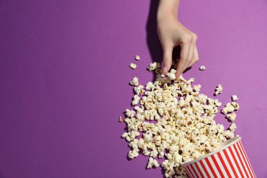 Menekşe arka planda lezzetli patlamış mısırlı bir kadın. Metin için boşluk