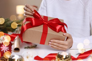 Beyaz masada Noel hediyesini paketleyen kadın, yakın plan.