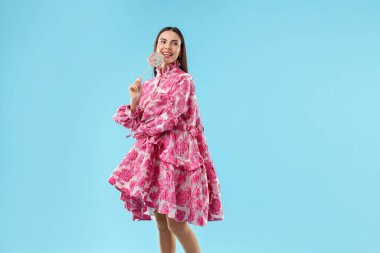 Açık mavi arkaplanda lolipopu olan güzel kadın, metin için boşluk