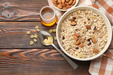 Tahıl yapıyorum. Yulaf gevreği, kurutulmuş meyve, badem fıstığı ve tahta masa üzerinde bal, düz bir yatak. Metin için boşluk