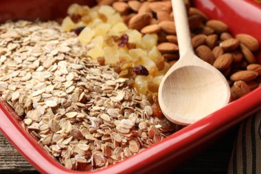Tahıl yapıyorum. Yulaf ezmesi, kurutulmuş meyve ve badem fıstığı ahşap masada, yakın plan.