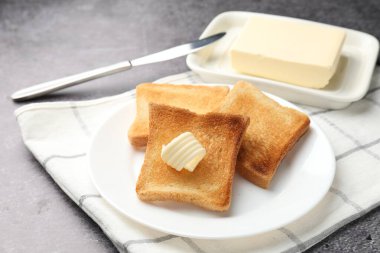 Gri masadaki tereyağlı taze ekmek dilimleri, yakın plan.