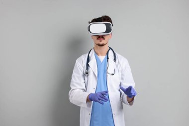 Modern teknoloji. Doktor gri arka planda sanal gerçeklik kulaklığı kullanıyor