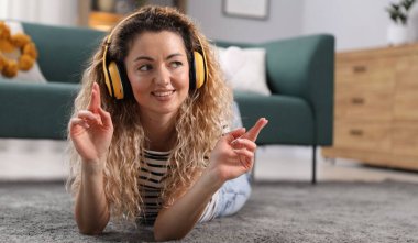 Kulaklıklı mutlu kadın evde yerde müzik dinliyor. Metin için boşluk