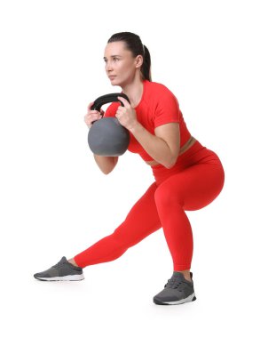Beyaz arka planda kettlebell egzersizi yapan atletik kadın.