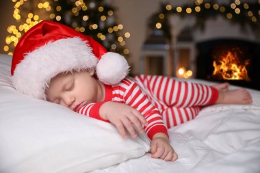 Noel pijamalı bebek ve Noel Baba şapkalı evde uyuyan bebek.