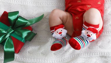 Noel Baba şapkalı bebek ve Noel dekoru yatağın üstünde.