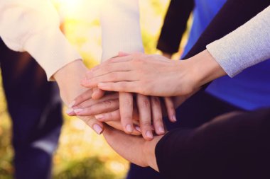 Güneşli bir günde dışarıda el ele tutuşan bir grup gönüllü, kapatıyorlar.