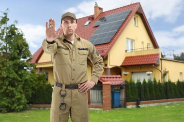 Dışarıdaki evin önünü kapatan üniformalı bir güvenlik görevlisi. Özel mülk koruması