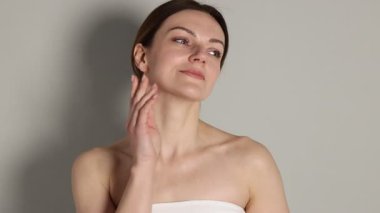 Açık gri arka planda normal tenli güzel bir kadın.