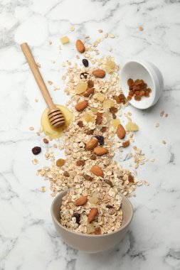 Tahıl yapıyorum. Yulaf ezmesi, kurutulmuş meyve, badem fıstığı ve balla bembeyaz mermer masa üzerinde yassı kompozisyon