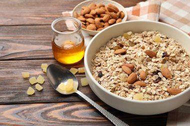 Tahıl yapıyorum. Yulaf gevreği, kurutulmuş meyve, badem fıstığı ve bal ahşap masada, yakın plan.