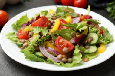 Gri masada mercimek ve sebzeli lezzetli salata, yakın plan.