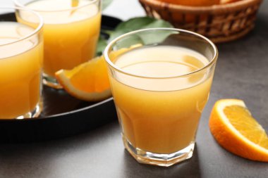 Taze portakal suyu ve meyveler gri masada, yakın plan.