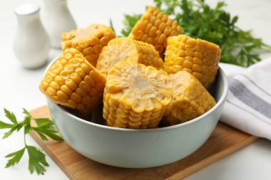 Lezzetli mısır koçanları ve maydanozlar beyaz masada, yakın plan.