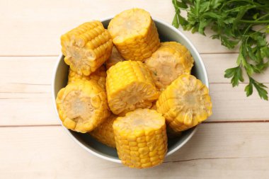 Lezzetli mısır koçanları ve maydanoz parçaları beyaz ahşap masa üzerinde, düz yatıyordu.