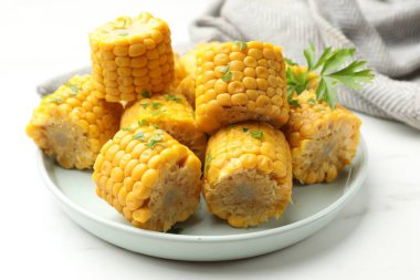 Beyaz masada maydanozlu mısır koçanları, yakın plan.