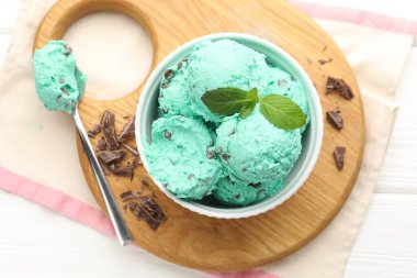 Çikolata parçalı lezzetli dondurma, beyaz ahşap masada kaşık ve havlu.