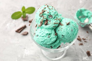 Çikolata parçalı lezzetli dondurma ve gri desenli masaya kepçe, yakın plan.