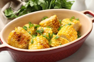 Beyaz masada yeşil soğanlı ızgara mısır koçanları, yakın plan.