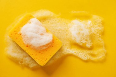 Turuncu arka planda köpüklü mutfak süngeri, üst manzara. Metin için boşluk