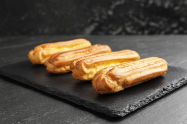 Tasty eclairs on black table. Delicious dessert