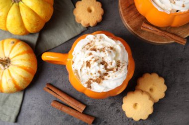 Balkabaklı latte, fincanda krema, baharat, kurabiye ve taze sebzeler, koyu dokulu masa, düz uzanmış.