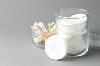 Açık gri arka planda temiz pamuk, bez ve kozmetik ürünler, yakın plan. Metin için boşluk