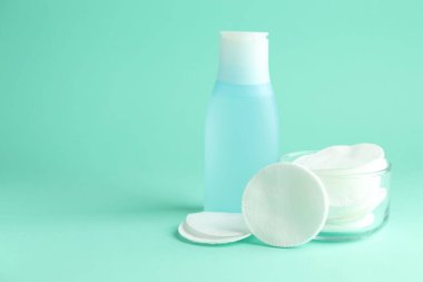 Turkuaz arka planda temiz pamuk pedleri ve mikiler suyu. Metin için boşluk