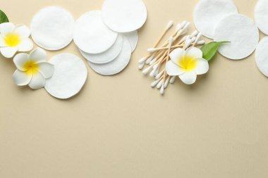 Temiz pamuk pedleri, bej arka planda bezler ve çiçekler, düz yatış. Metin için boşluk