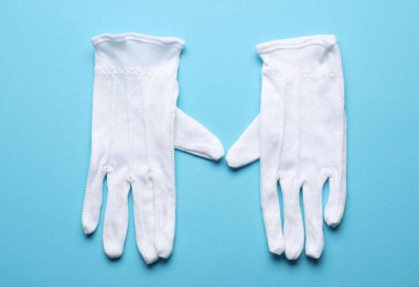 Açık mavi arka planda beyaz kumaş eldivenler, üst manzara.