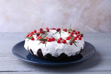 Gri ahşap masada yaban mersinli ve biberiyeli lezzetli Noel pastası, yakın plan.